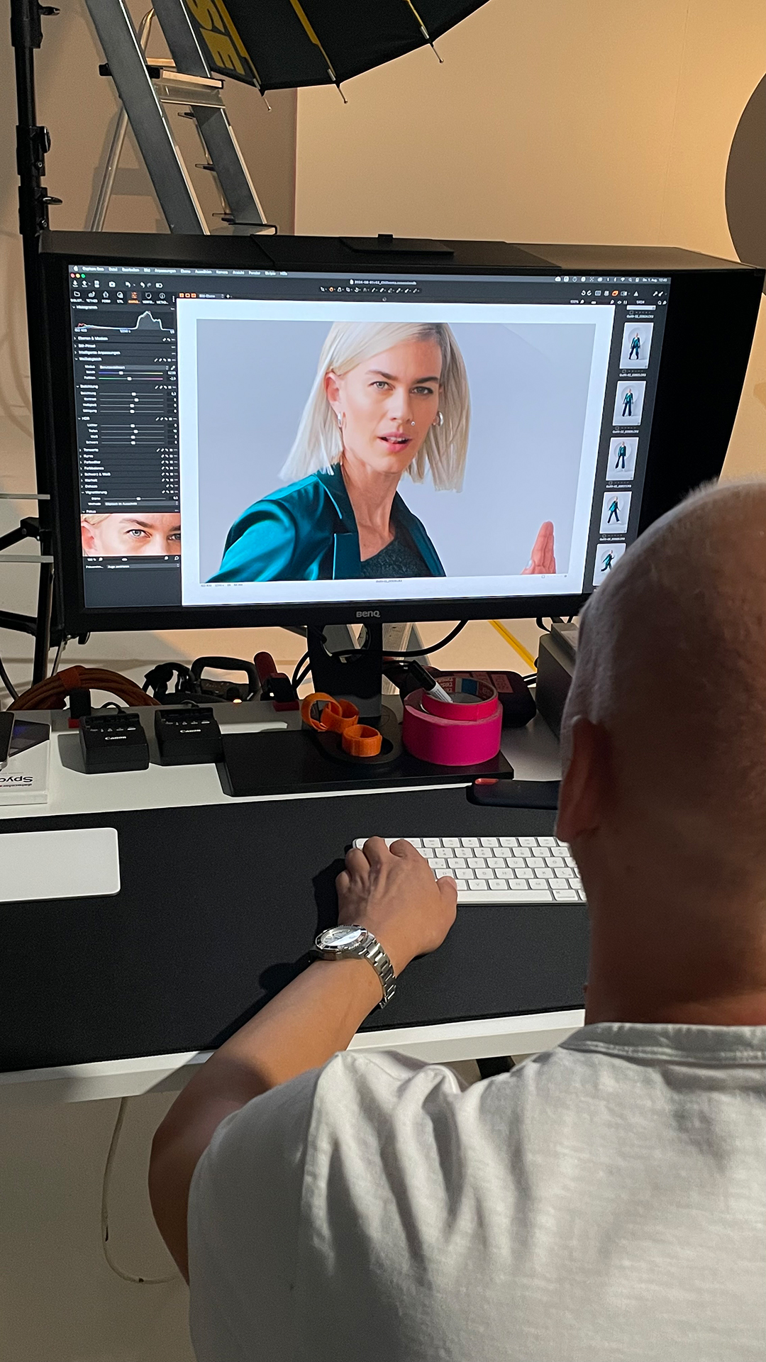 Mann arbeitet an einem Monitor mit großem Porträtfoto einer Frau in einer Bildbearbeitungssoftware.