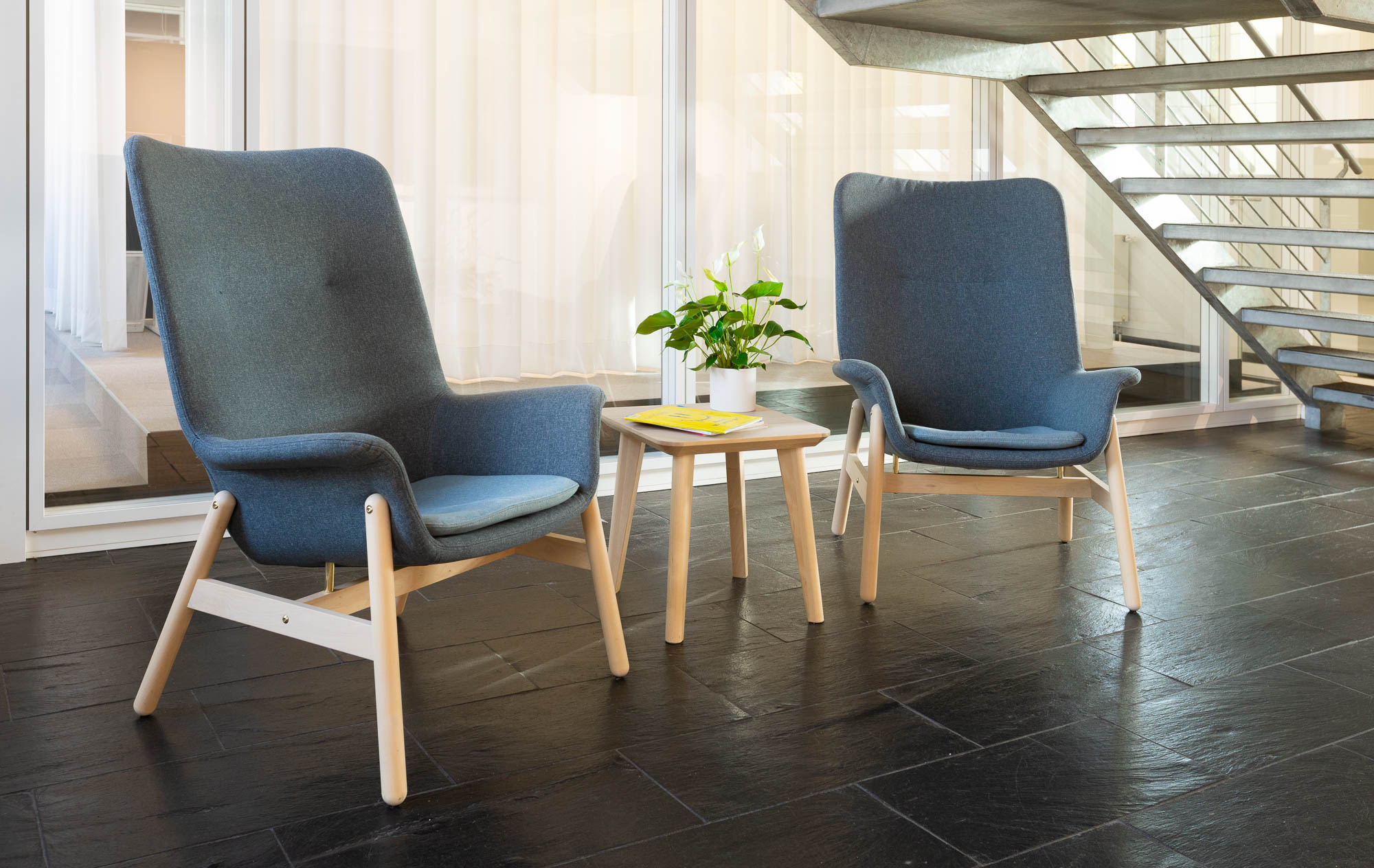 Heller Loungebereich mit zwei modernen Sesseln und kleinem Beistelltisch.